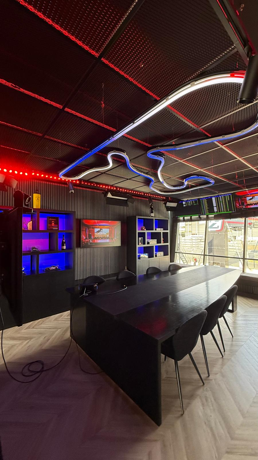 Private VIP lounge at Circuit Zandvoort with neon track silhouette ceiling and panoramic pit lane view