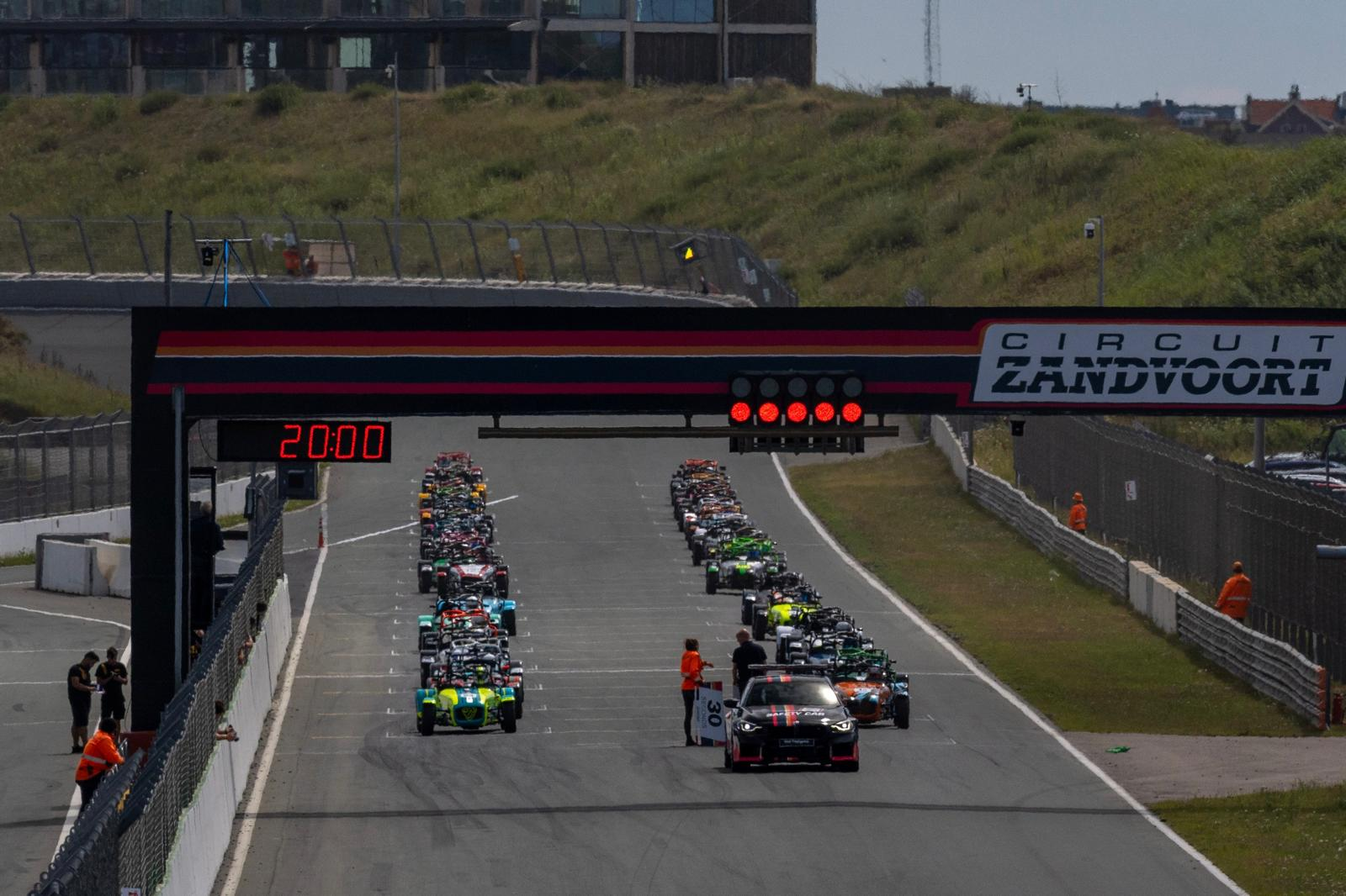 Full grid lined up under the Circuit Zandvoort start gantry, lights on, ready to race